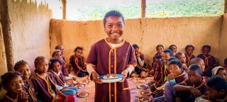 Children sit to eat food in school