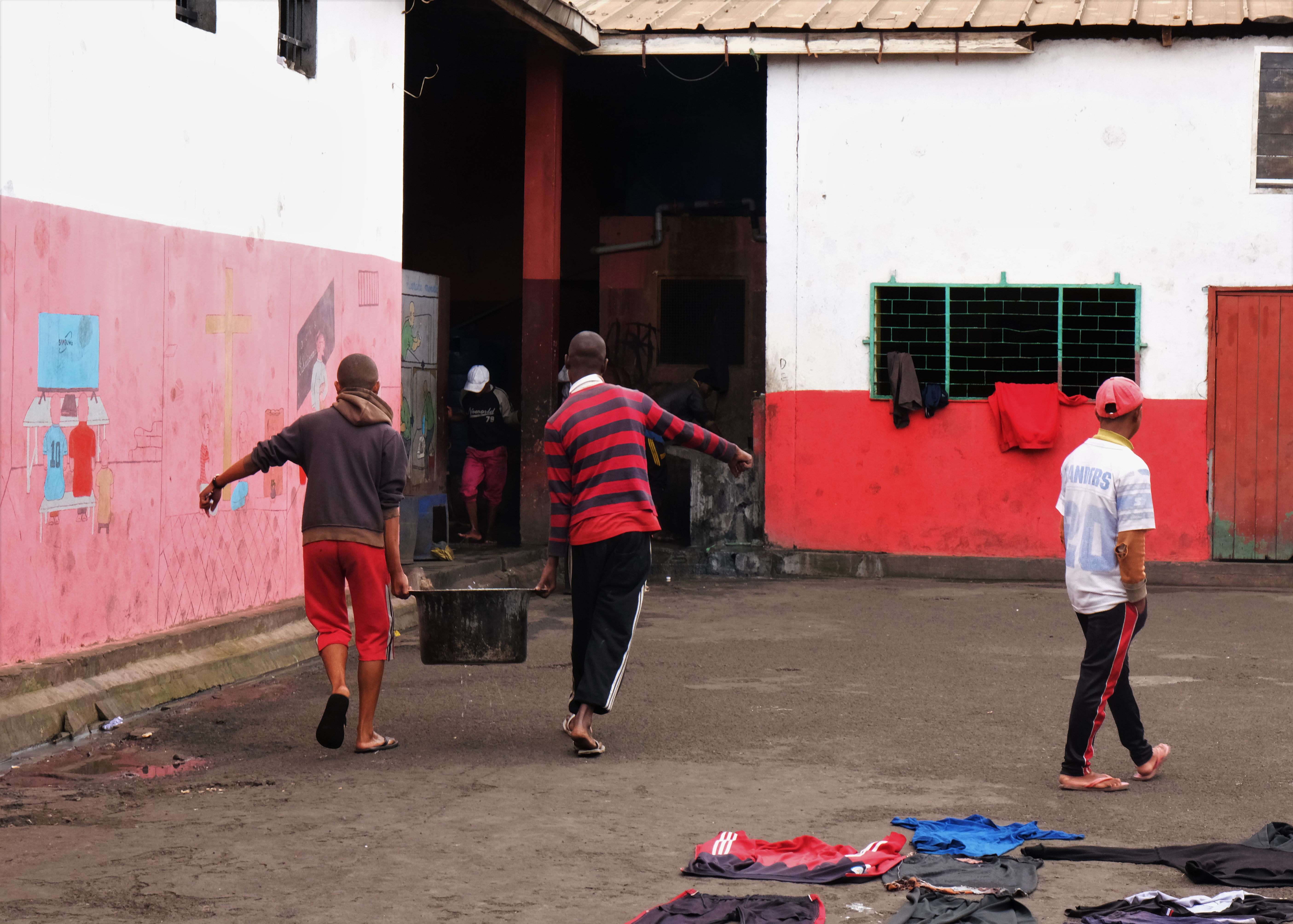 two men carrying a large pot in a yard