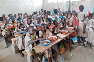 a classroom full of children with plates of food in front of them