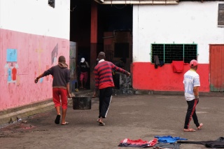 two men carrying a large pot in a yard