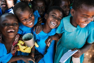 Children receiving a meal, smiling and laughing together.