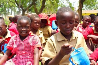 Children sitting outside at school eating food.