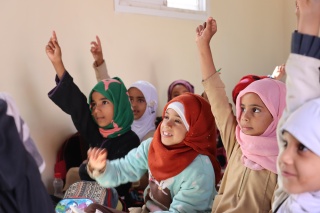 group of girls in class with their hands raised