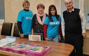 four people posing for a photo in front of a table laden with baked goods