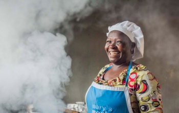 A volunteer cook laughs as she prepares food