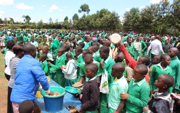 a large group of children gathering receiving school meals