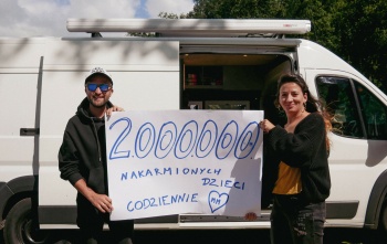 two fundraisers standing in front of a van and holding up a sign that reads "2000000"