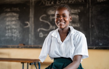 young girl in class smiling as she poses for a photo