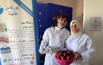 Two female volunteers holding bowls of food and posing for a photo