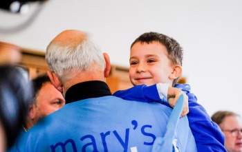 A volunteer carries his grandson at a fundraising event