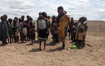 Children in the rural region of Turkana in Kenya standing together against the backdrop of a dry, arid desert landscape.