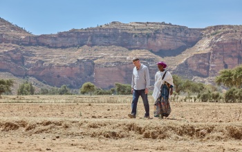 a man and woman walking in harsh looking desert climate