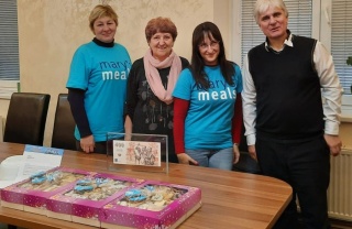 four people posing for a photo in front of a table laden with baked goods