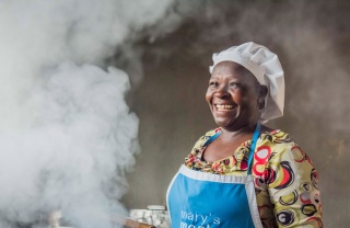 A volunteer cook laughs as she prepares food