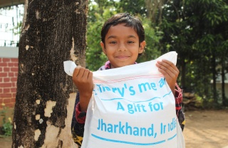 A boy in India holds a delivery of food from Mary's Meals
