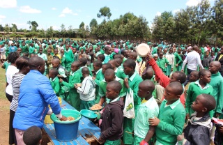 a large group of children gathering receiving school meals