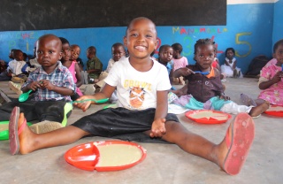 children in class sitting on the floor with plates of food in front