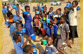 group of children holding brightly coloured mugs up to the camera