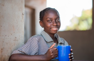 young girl holding a blue mug