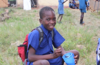 A child from Zambia enjoying Mary's Meals in their place of learning.