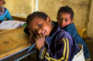 A young boy rests against a table in class
