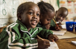 A child eagerly takes notes in class