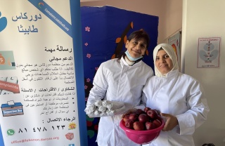 Two female volunteers holding bowls of food and posing for a photo