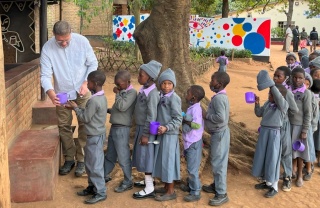 line of children waiting to receive servings of food outdoors