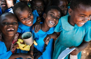 Children receiving a meal, smiling and laughing together. 