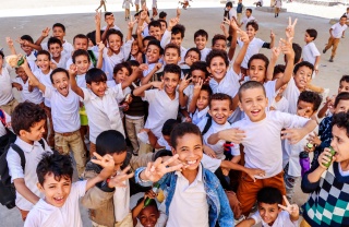 Large group of children smiling and looking into camera.