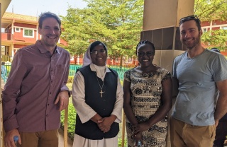 Sister Gracy standing with Mary's Meals partners looking into camera. 