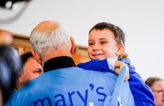A volunteer carries his grandson at a fundraising event