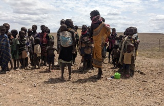 Children in the rural region of Turkana in Kenya standing together against the backdrop of a dry, arid desert landscape.