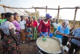 group of people standing around a freshly made cauldron of porridge