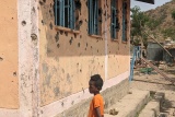 Boy in Tigray standing next to building with bullet holes