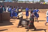 Volunteer cooks carrying a pot of cooked food ahead of serving meals to the children. 