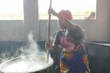 A volunteer cook stirs a pot over a stove, preparing meals for the children. 