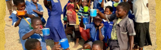 group of children holding brightly coloured mugs up to the camera