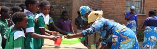 Children being served Mary's Meals at school in Malawi. 