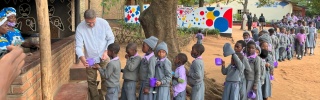 line of children waiting to receive servings of food outdoors