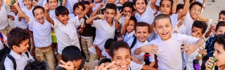 Large group of children smiling and looking into camera.