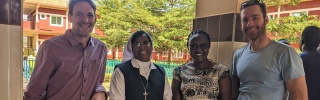 Sister Grace standing with Mary's Meals partners looking into camera. 