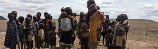 Children in the rural region of Turkana in Kenya standing together against the backdrop of a dry, arid desert landscape.