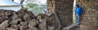 Mary's Meals volunteer standing in a building where one of the walls has collapsed.