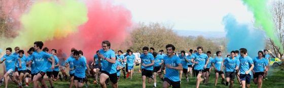 group of fundraisers racing from the start line with coloured smoke plumes overhead