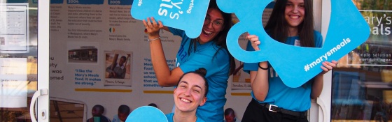 A group of Mary's Meals volunteers smiling and holding Mary's Meals mugs