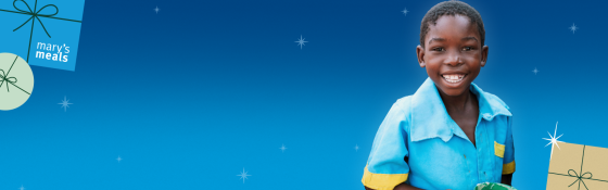 A child smiling against a blue backdrop, with some christmas iconography