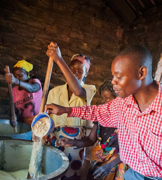 volunteers stirring a large cauldron of porridge