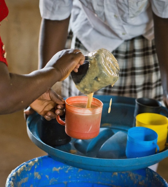 A volunteer from Zambia serving Mary's Meals to children at school. 