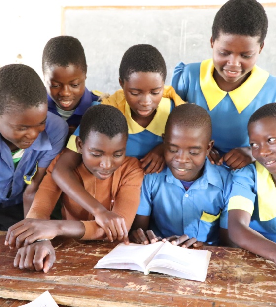 Ulemu with his classmates reading a book. 
